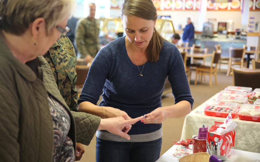 Adrea Facio (right), military spouse on Marine Corps Logistics Base Barstow, Calif., demonstrates her nail products to, Cheryle Magorno, a multimedia specialist on MCLB Barstow, at Marine Corps Family Team Building's Spouse in the House event at the base Family Restaurant, Nov. 13. The purpose of the event was to let military spouses who live on base promote personal businesses or services they run from in the home.