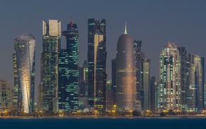 Skyline of the arabian city of Doha night to day transition timelapse in Qatar, captured in the very early morning before sunrise with illuminated skyscrapers. View from Corniche Promenade