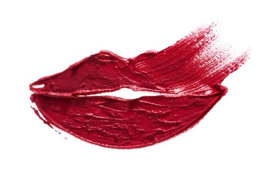 A textured smear of red lipstick on white paper in the shape of lips 