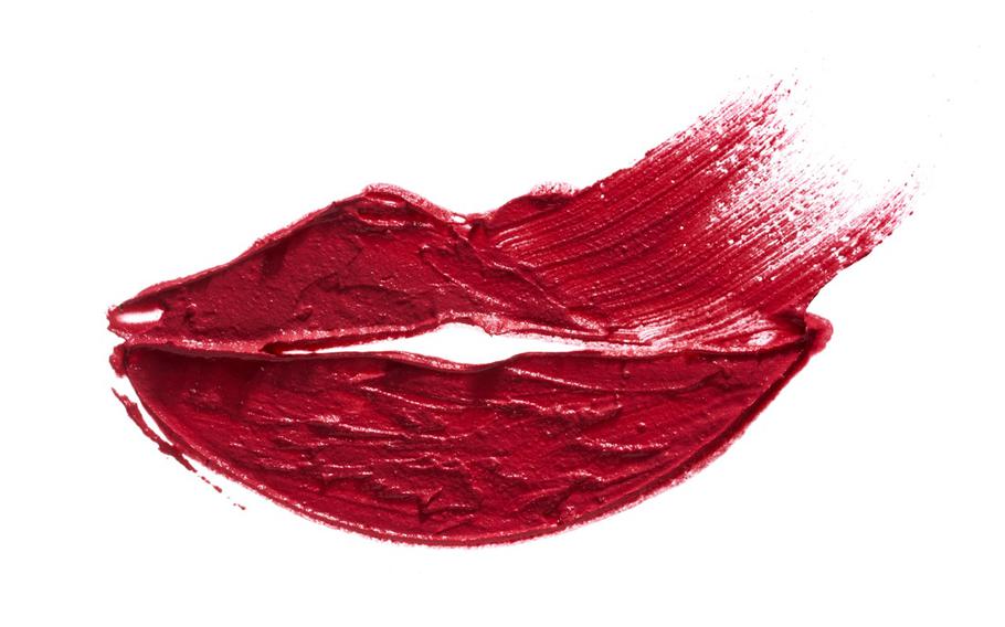 A textured smear of red lipstick on white paper in the shape of lips 