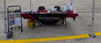 Stars and Stripes table with all the swag on the table and a small rack of magazines of the left side