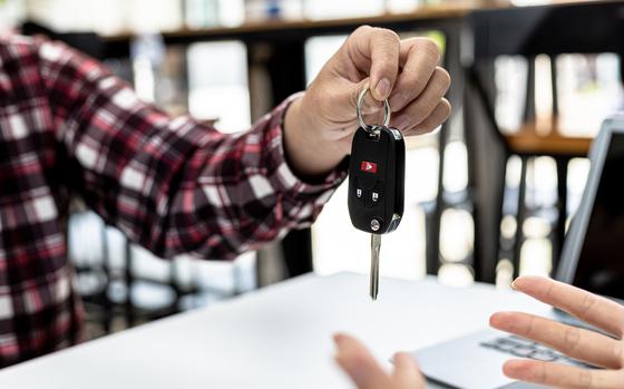 Person holding the car key to the car rental company employee, the customer who has completed the rental car has returned the car to the company and pre-checked, car rental service concept.