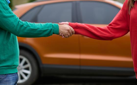 Car keys handshake, seller or car salesman and customer in a dealership, shake hands over the car keys and seal the purchase of the auto or new car. 