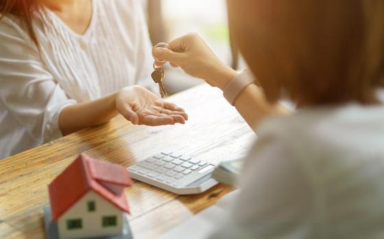 A new landlord receives a house keys chain from a real estate broker after paying a house deposit. Realtor and client, Real estate investment.