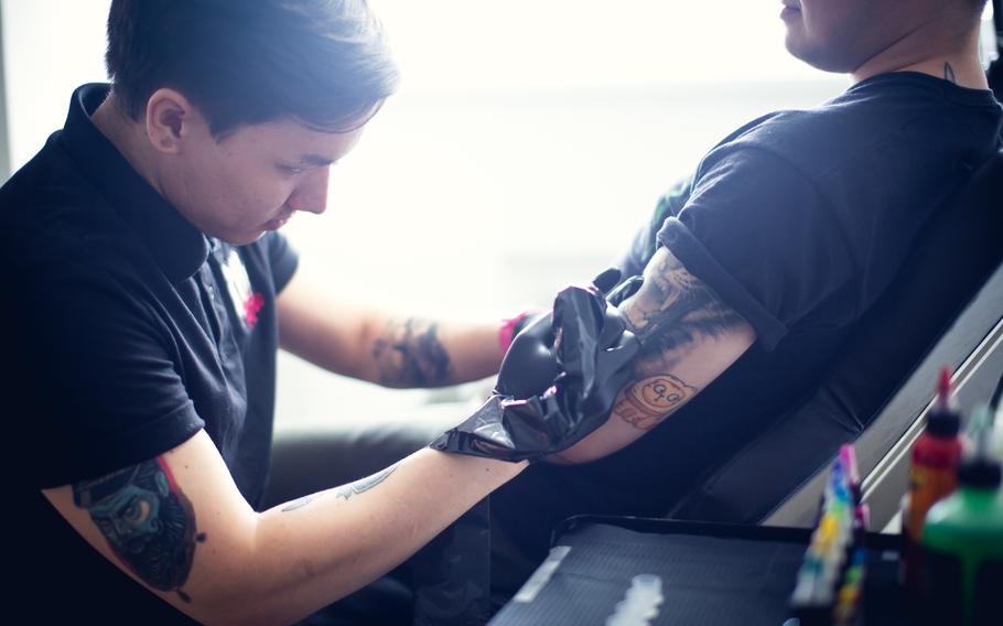 Tattoo artist tattooing on client’s arm