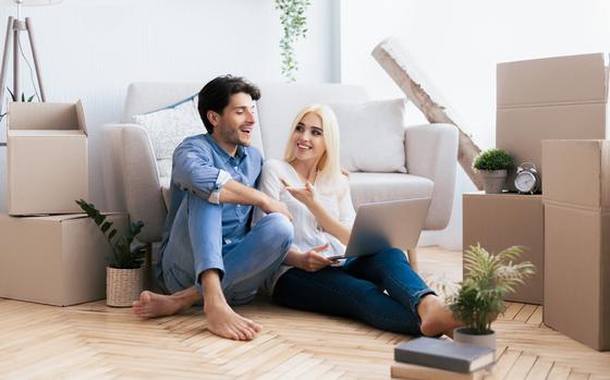 Couple sitting on floor in front of furniture and moving boxes