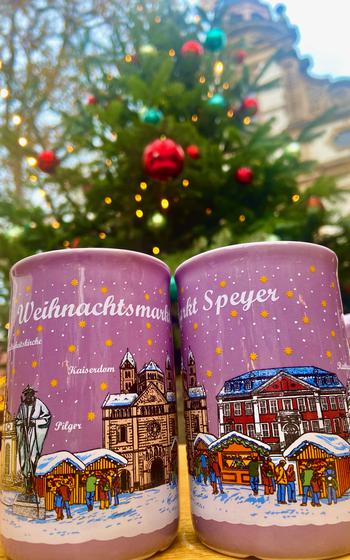 Up-close shot of two light purple Christmas mugs set against a Christmas Tree. 