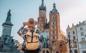 Back view of traveler woman walking on old Market Square in Krakow holding tourist map.