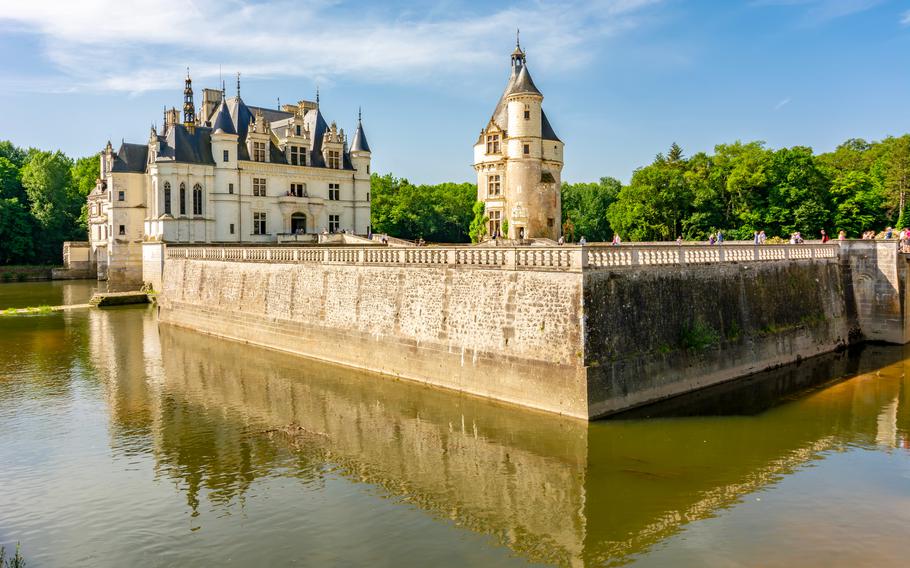 A view of the white and gold castle surrounded by a moat of water