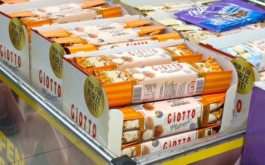 Assorted european chocolate and biscuit display in supermarket aisle.