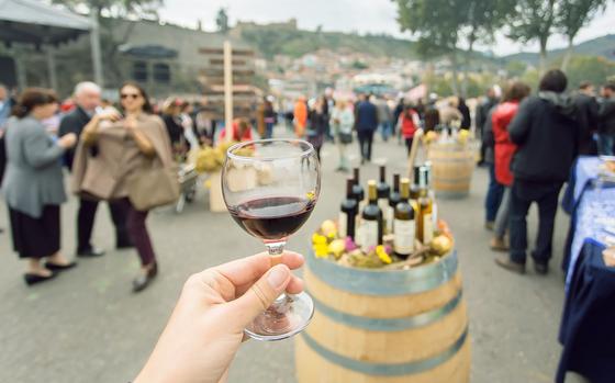 Glass of wine at tasting area of annual city festival Tbilisoba with crowd of people around. Tbilisi, the capital of Georgia country
