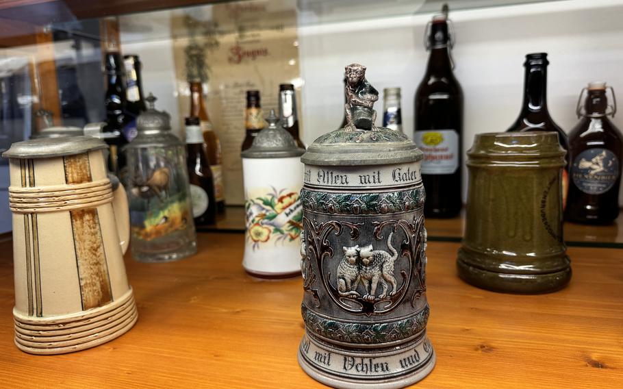 Beer steins on display focusing on a medieval design with two cats