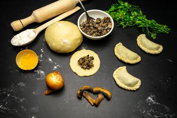 Dumplings on a black background with mushrooms, dough and filling for dumplings