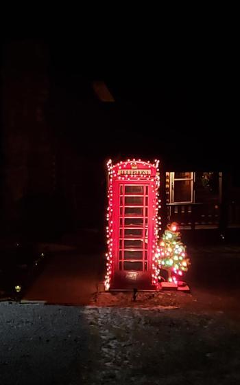 K-6 Phonebooth at Christmastime; red phonebooth lit up with Christmas light with a miniature Christmas tree next to it.