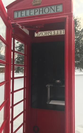 Inside the K-6; a black telephone inside a red phonebooth with an opendoor