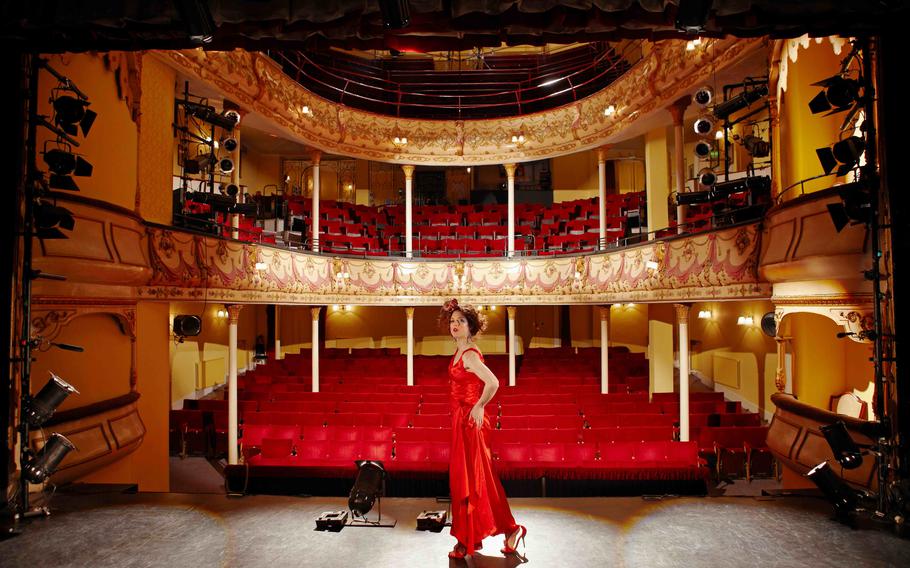 Full length side view of a woman in red gown on stage floor