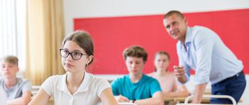 Focus on a female student with glasses sitting at desk