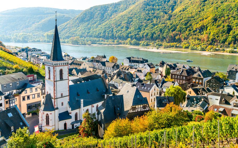an overview of a town with half-timbered houses along the rolling hills and Rhine river with a white, spired church as the focal point 