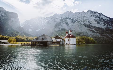 Photo Of Classic panoramic view of Lake Konigssee with world famous Sankt Bartholomae pilgrimage church and Watzmann mountain in beautiful golden evening light at sunset in summer, Berchtesgadener Land, Bavaria, Germany