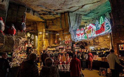 Photo Of A cozy light brown cave decorated with Christmas lights and Santa, many people are gathered shopping small stalls. 