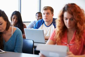 Male university student using laptop in classroom