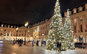 a view of a tan courtyard in Paris with two green, sparkly, lit up christmas trees