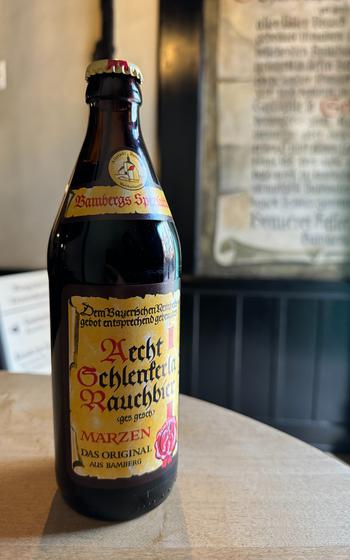 a beer bottle with medieval script on the label siting on a table 