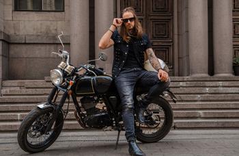 Tattooed biker in sunglasses sitting on his motorcycle