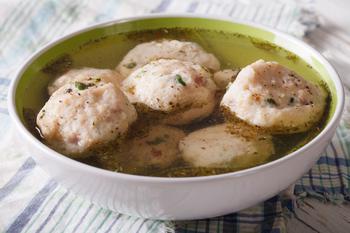 Close up of bread dumplings canederli in a broth in a bowl.