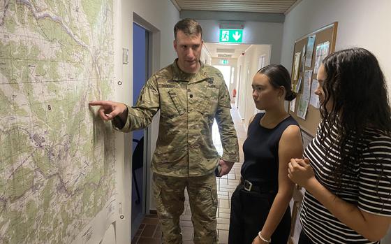 U.S. Army Lt. Col. Doug Droesch (left) familiarizes new employees, Alexis Ellerston (middle) and Gianna Villa (right) of the U.S. Army Europe and Africa Summer Hire Program, with the layout of the Hohenfels Training Area at the Joint Multinational Readiness Center near Hohenfels, Germany on June 22, 2023.