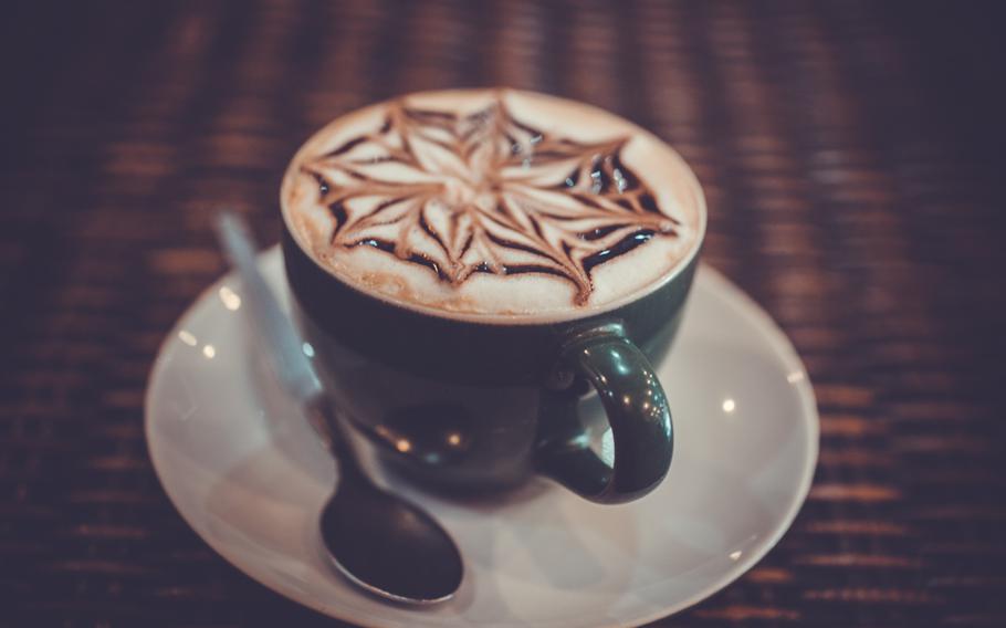 Cup of coffee latte with design art in froth, on a wooden table