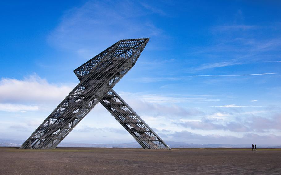 a metal structure stands tall on a hill with a wide-opened sky background