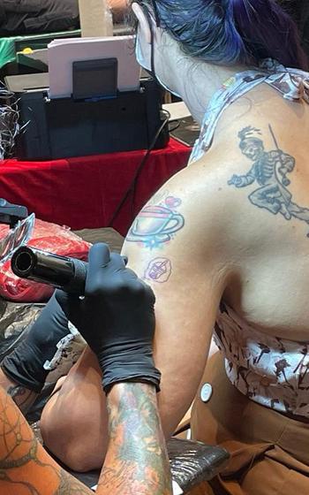 Tattoo artist tattooing arm