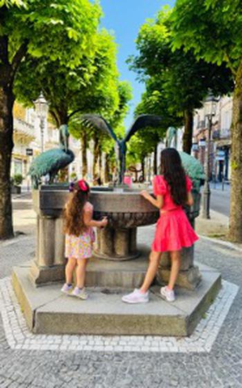 Two girls looking into a fountain on a sunny day