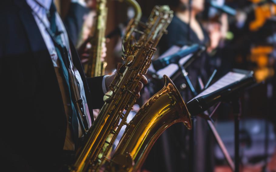 Concert view of a saxophonist, saxophone player with vocalist and musical during jazz orchestra performing music on stage