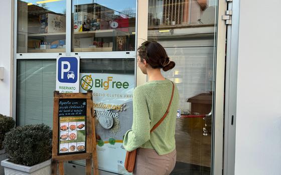 a woman entering into the grocery store with gf specials on a sign outside
