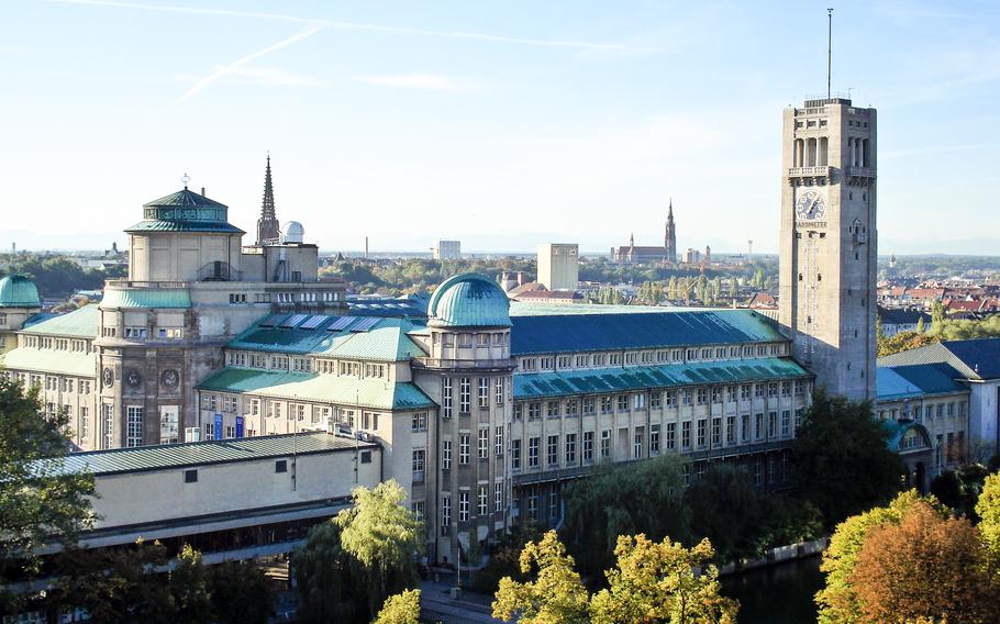 The Deutsches Museum in Munich: A stunning historical building located on an island in the Isar River, featuring green domes and a prominent clock tower. Surrounded by lush trees, this iconic museum houses the world’s largest collection of science and technology exhibits, offering a perfect blend of architecture, culture, and innovation.