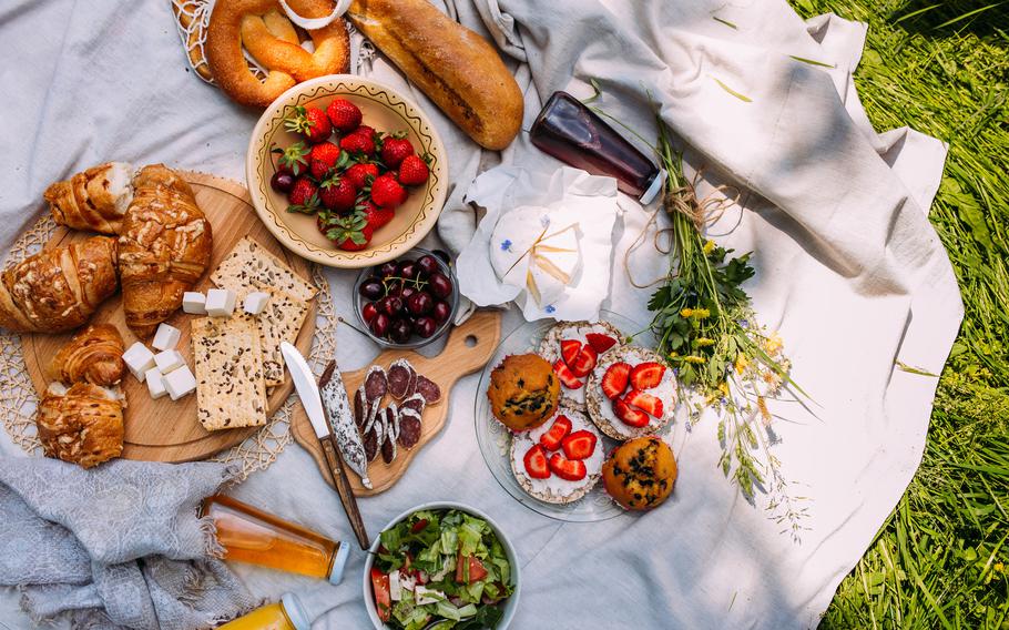 Picnic in the field with berries, juice, cheese, sausage and sweet croissants.