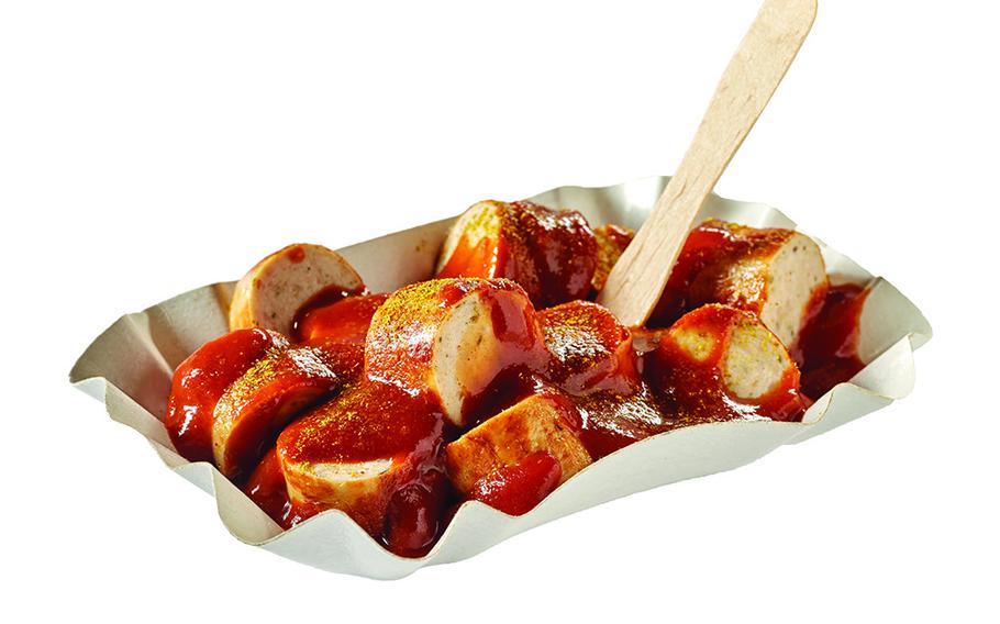 Delicious curried pork sausage pieces with ketchup and eco stick in takeaway bowl on white background