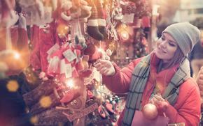 Girl wearing winter clothing shopping for Christmas decorations at a stall.