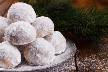 Indulge in the rich tradition of Kourabiedes, a classic Greek treat perfect for the holiday season. These buttery almond shortbread cookies are coated in a generous layer of powdered sugar, creating a delicate, melt-in-your-mouth texture. Set against a rustic dark wooden background, the warm tones highlight their festive elegance and irresistible charm. Perfectly balanced with the crunch of roasted almonds, Kourabiedes are a timeless favorite, evoking the warmth of family gatherings and holiday cheer. Whether for a special celebration or a cozy indulgence, these cookies bring a taste of Greek tradition to your table.