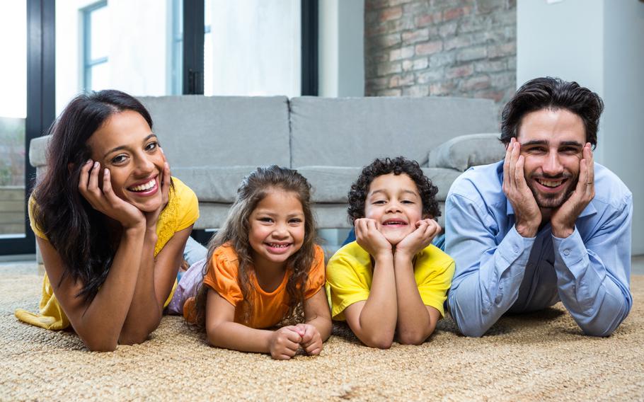 Smiling family on carpet in living room posing for the camera