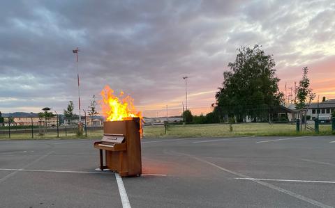 Photo Of Burning piano at dusk in a parking lot