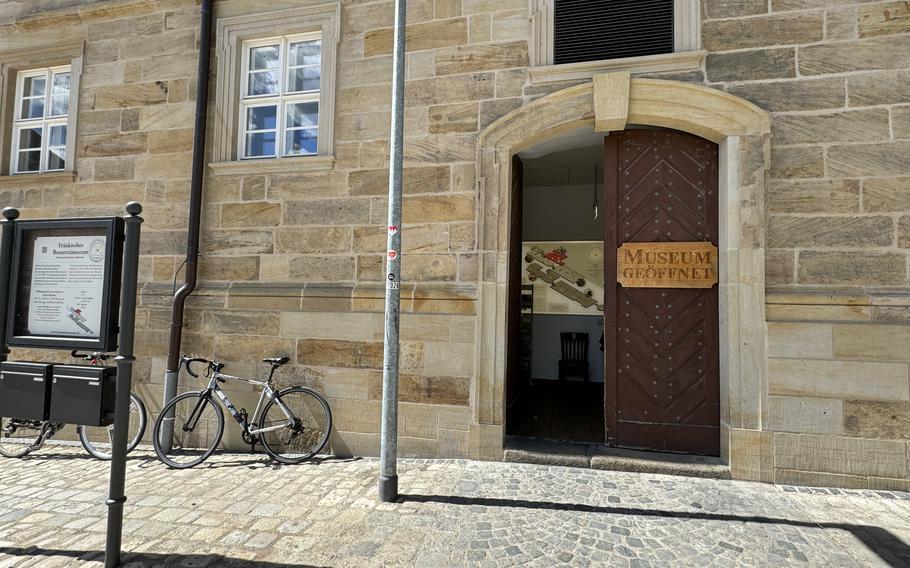 The museum entry door with bikes leaning against the sandstone-colored wall. 