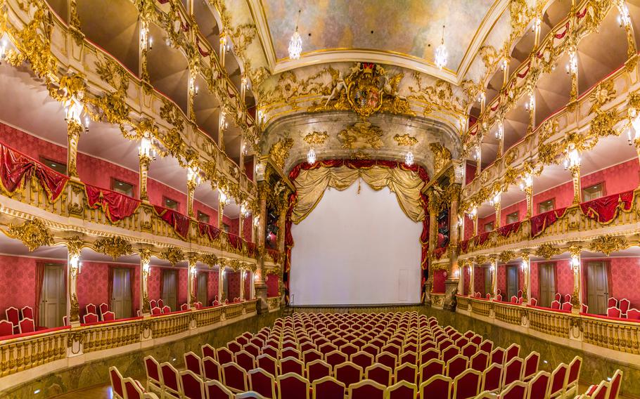 A large theatre with a stage where the floor to cieling is gold and red with adornments. 