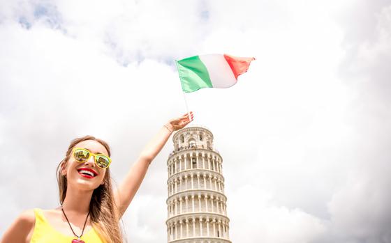 Photo Of Female traveler with Italian flag near the famous Leaning Tower of Pisa  in Italy. 