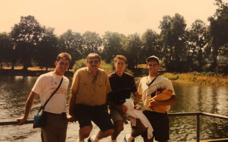 Four men standing at a lake