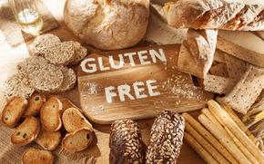 A picture of a cutting board with “Gluten Free” spelled in flour surounded by various types of bread. 