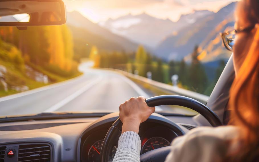  Woman driving car on scenic mountain road. 