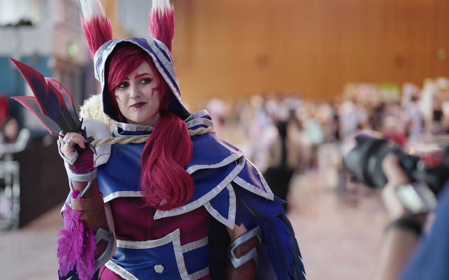 A woman poses in a Home made cosplay mask Xayah from League of Legends pose at comic con